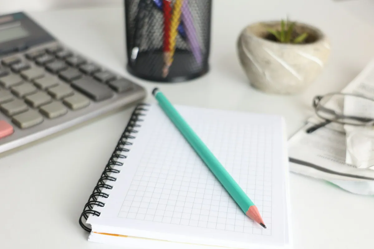 Open planning notebook, pencil and calculator on a desk