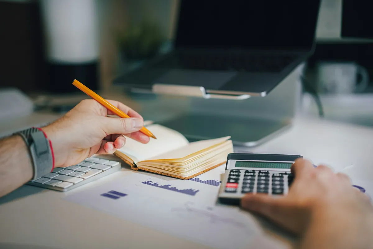 Person checking figures with a calculator and notebook